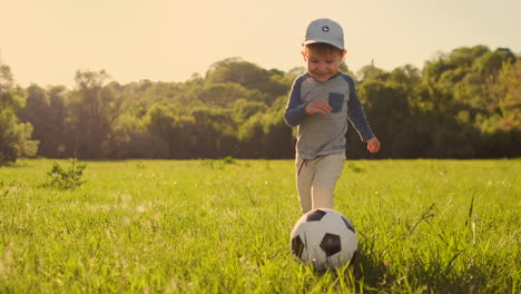 The-boy-runs-with-a-soccer-ball-laughing-at-the-sunset-in-slow-motion.